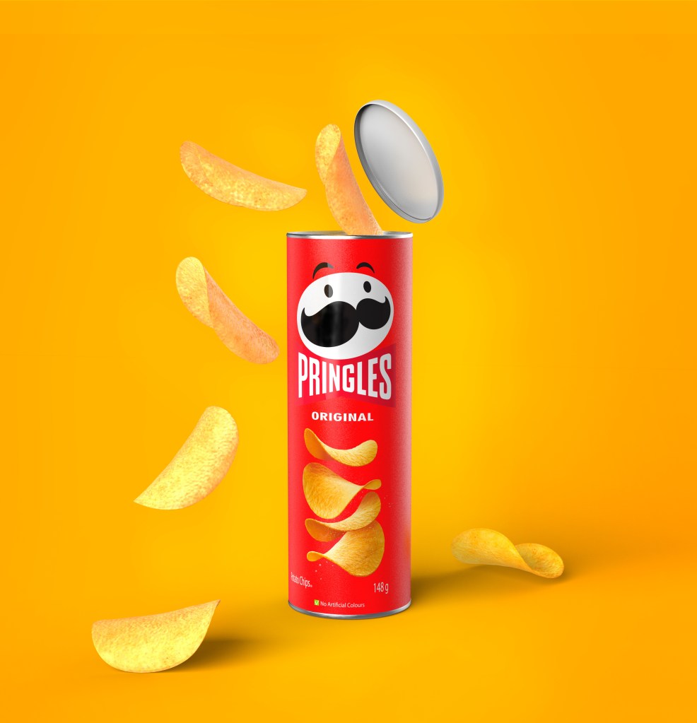 Open package of Pringles crisps with poured chips, on a yellow background